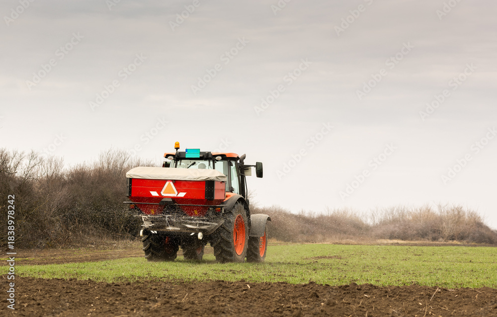 Fototapeta premium Tractor spreading artificial fertilizers in field