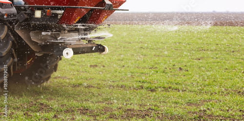 Tractor spreading artificial fertilizers in field