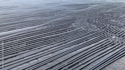 Installing ice rink for winter season. Early stages of installing refrigeration system. Black PVC pipes is laid, they connect ends to larger main header pipe to form complete cooling loop.
