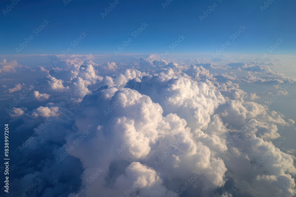 Fototapeta premium Aerial view of white fluffy clouds under a clear blue sky with sunlit edges