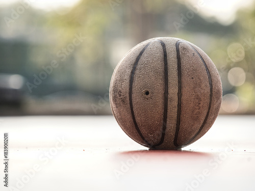 Old basketball on the court has standing water.