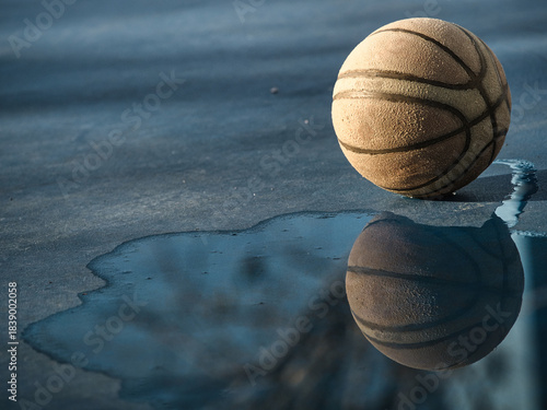 Old basketball on the court has standing water.