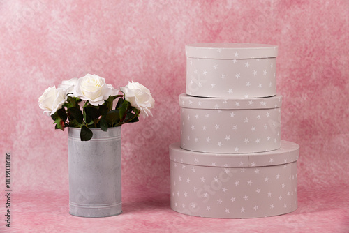 Florero con rosas blancas y cajas de regalo.