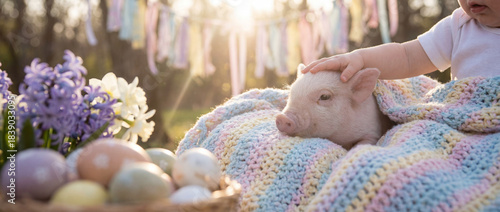 Child touches piglet on blanket surrounded by flowers and eggs