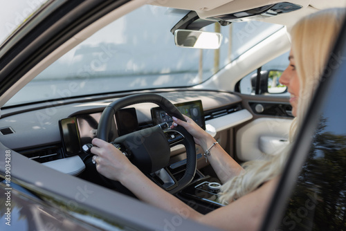 Woman with long hair drives a car while sitting in the driver's seat. She looks focused and attentive.