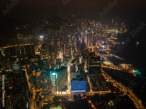 Aerial view of a sprawling cityscape, illuminated by countless lights, casting a golden glow over the harbor and the skyscrapers of Hong Kong Island, Hong Kong Island, Hong Kong.