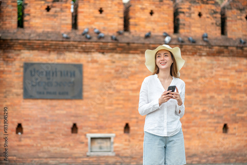 Young Asian Woman Tourist Using Phone at Tha Phae Gate in Chiang Mai Thailand