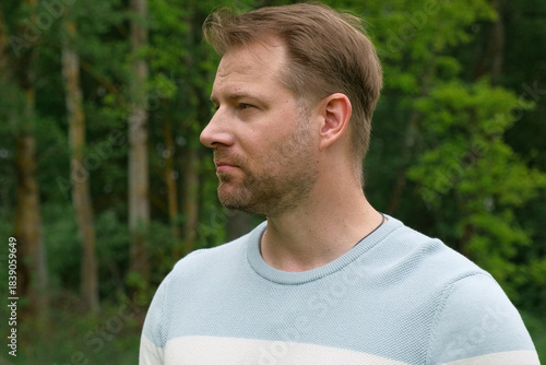 Handsome young man standing outdoors. Male thinking looking around feel happy, calm and serious. Green park background. Guy business employer, businessman manager inspired in nature. Diversity People