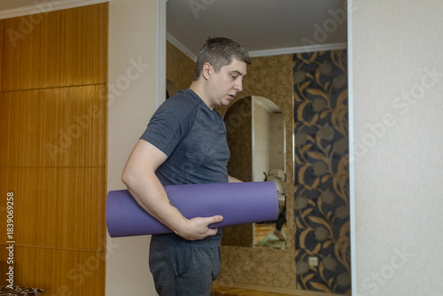 Plus-size man practicing yoga at home on a mat, stretching to improve flexibility, joint mobility and posture. Concept of home fitness, rehabilitation, wellness and mindful movement.