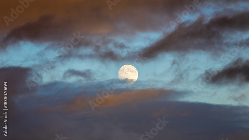 Large moon is visible in the sky above a cloudy, dark blue sky