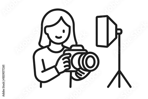Smiling woman photographer operating camera with professional studio lighting equipment