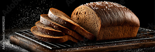 Sliced loaf of dark rye bread on a wire cooling rack with salt on top against black background
