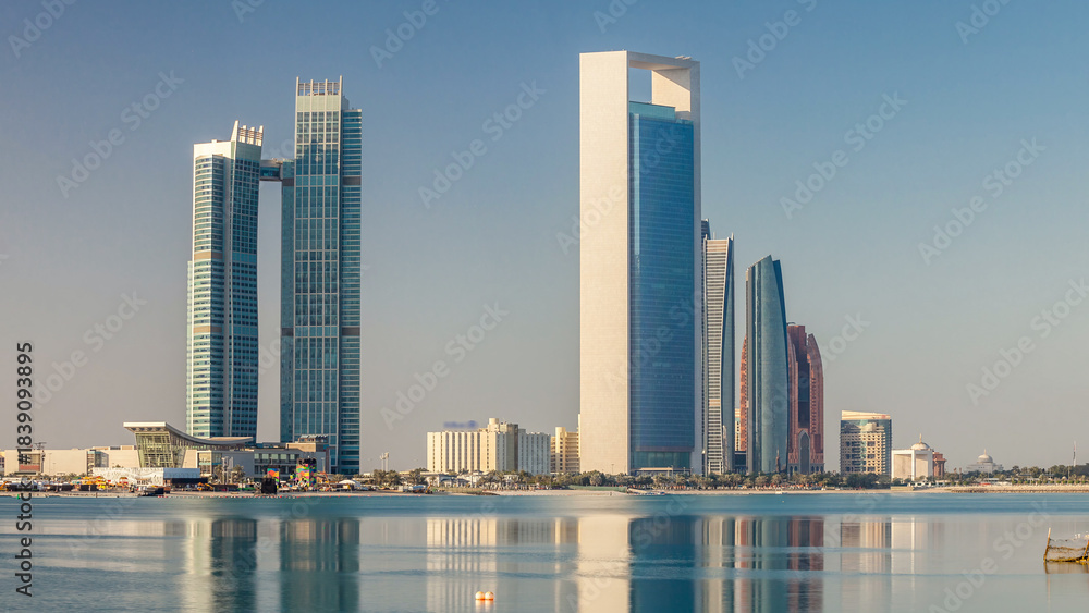 Naklejka premium Abu Dhabi city skyline with skyscrapers after sunrise with water reflection timelapse