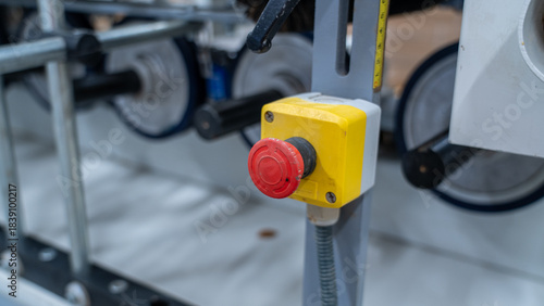 Emergency stop button on industrial machine with rollers and metal frame