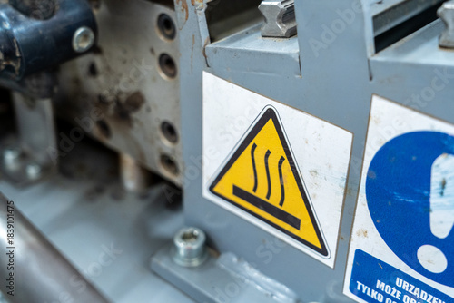 Industrial hot surface warning sign on metal machinery in factory environment