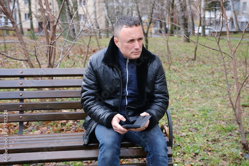 autumn man leather jacket latin man on a bench talking on a serious phone, waiting for someone to call him. High quality 4k footage