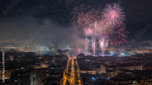 Aerial view of a cityscape in Italy with vibrant fireworks exploding over buildings and streets on New Year's Eve at night.