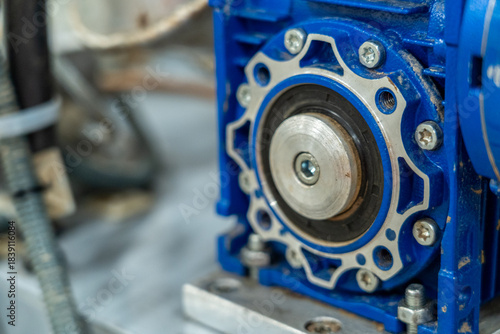 Close-up of blue industrial gearbox and output shaft in manufacturing machine