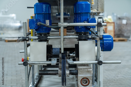 Front view of industrial processing machine with blue electric motors and metal rollers