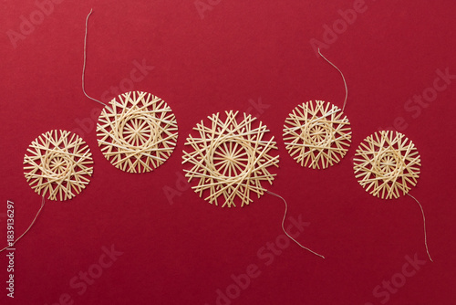 Straw snowflakes. Snowflakes are made of straw on a red background. Christmas decor. Top view. Straw weaving. Lutsk, Ukraine