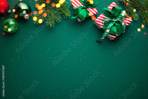 Merry Christmas and Happy Holidays greeting card, frame, border. New Year. Red Christmas ornaments and gifts, presents on green background top view. Xmas holiday festive theme. Christmas decoration