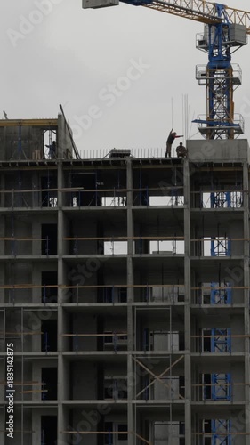 Real time vertical video of construction workers on highrise rooftop