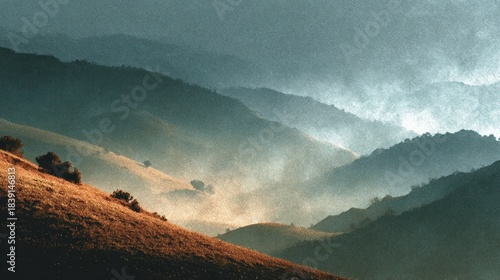 A mountainous landscape displays layered hills shrouded in mist, bathed in atmospheric light