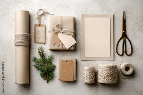 Neutral Eco-Friendly Holiday Gift Wrapping Flat Lay with Kraft Paper, Twine and Evergreen on Light Textured Background