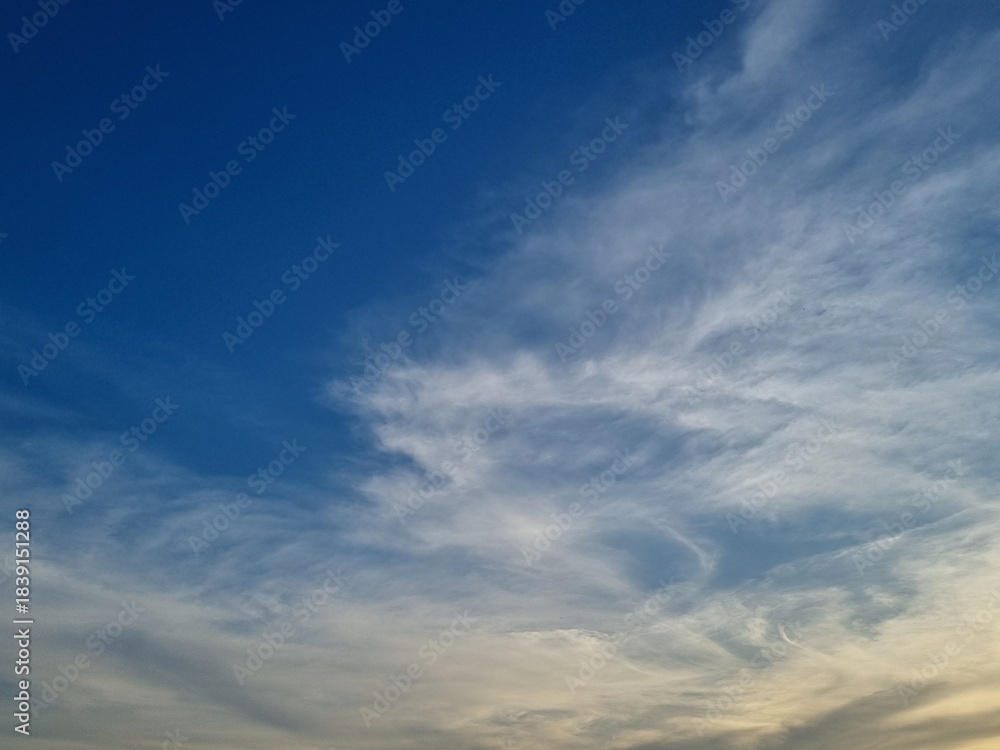 Obraz premium Celestial Symphony: A vast expanse of cerulean canvas adorned with ethereal, wispy clouds, a dance of light and shadow, invites contemplation and wonder.