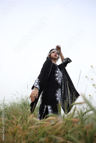 Young woman in traditional Central Asian clothing standing in nature