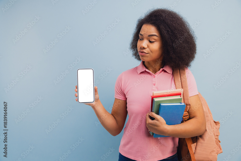 Naklejka premium Young student holding phone with books looking skeptical