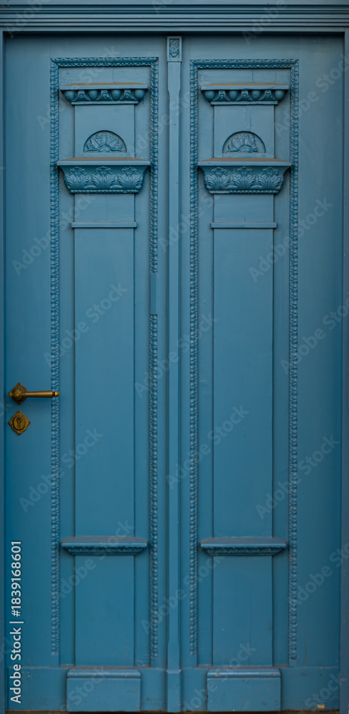 Fototapeta premium Blue carved doors with historic ornament in city facade. Vintage blue doorway.