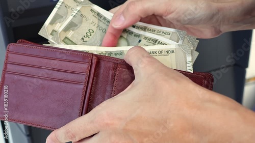 Close up view of woman hands, wallet and Indian rupee banknotes (INR) in ATM. Concept of saving money for retirement, cash settlement, financial goals, success, literacy and income planning in India.