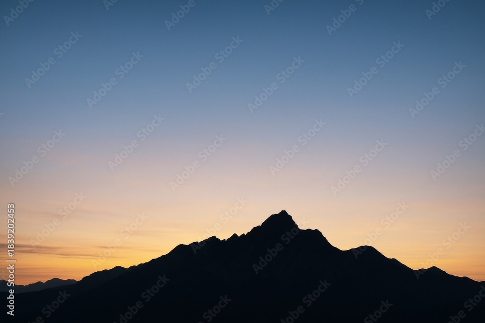 Obraz premium Silhouetted mountain range under soft gradient sunrise sky with wide copyspace and peaceful light for poster, banner, or background use. Ai generative