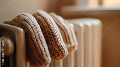 Warm knitted socks dry atop a white radiator, evoking cozy comfort in a sun-drenched room. The simple scene highlights everyday domesticity and the warmth of home.