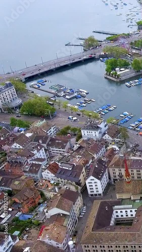 4K aerial vertical video of Zurich city center where Limmat River meets Lake Zurich. Cinematic drone view of Quaibrücke bridge, boats, and Old Town rooftops. Switzerland travel footage for mobile.