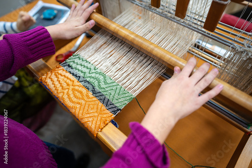 Fotografi Hands of child weaving on loom with joy of crafting