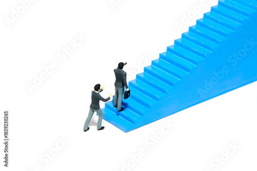 Miniature tiny people toys photography. Business support, teamwork. Businessman using binocular telescope start to walk the blue stairway. Isolated on a white background