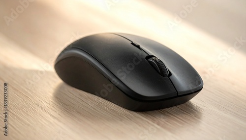 Black wireless computer mouse with scroll wheel on light wooden surface