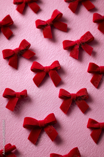 Velvety red bows placed across a pink surface for decorative and celebratory styling
