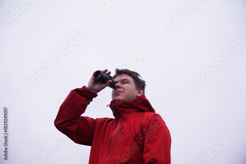 a man looking through binoculars on a white background. An observer, searching for new ideas, watching birds in nature