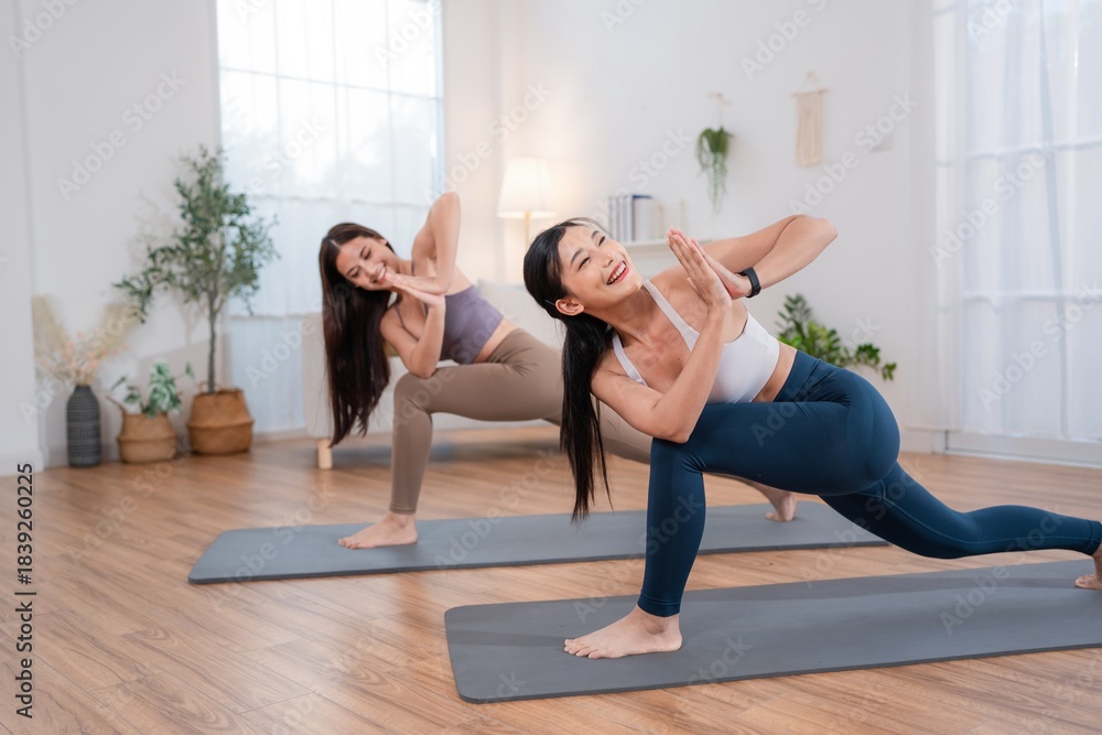 Obraz premium Two women practicing yoga in a bright studio during a daytime session for fitness and wellness
