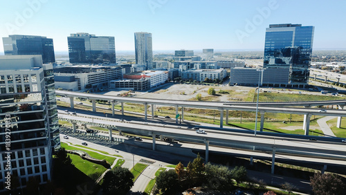 Schilderij op canvas Multi-level interchange looping ramps and directional traffic, office towers, parking decks, landscaped buffers
