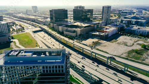 Rooftop HVAC units at modern office buildings mirrored glass border major highway 121 corridor, flanked by structured parking corporate, retails zones in dense metropolitan setting, Plano, Texas