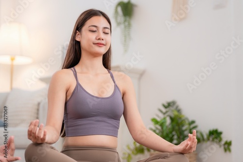 Free Download Young woman practices meditation in a bright room during the afternoon with plants in the background - GFXLoad