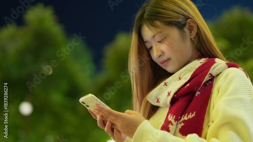  A young woman is happily using her phone at night.