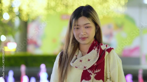  A young woman is happily using her phone at night.