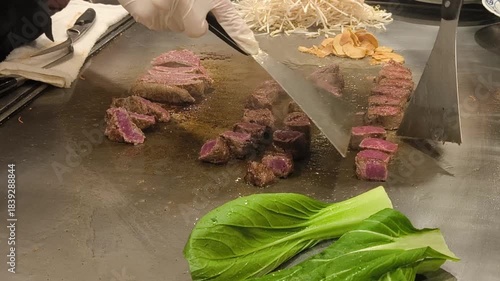 The chef sears Kobe beef on a hot grill, preparing it fresh for the omakase guest