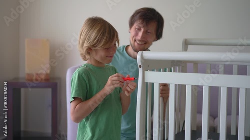 Father and son assembling a baby crib together for their soon arriving son and brother. Family teamwork, bonding, parenting support and preparation for newborn concept.