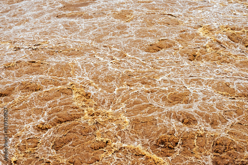 Smudged water flows profusely. River water flowing profusely. Flood waters rushing down river after storm flows through. Turbulent river dam. Water turbulence of river due to dam. Water Nature Texture